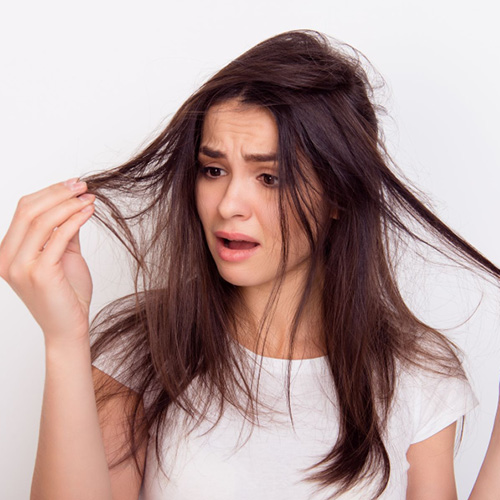 Ragazza bruna con la faccia infastidita che si guarda i capelli visibilmente alterati