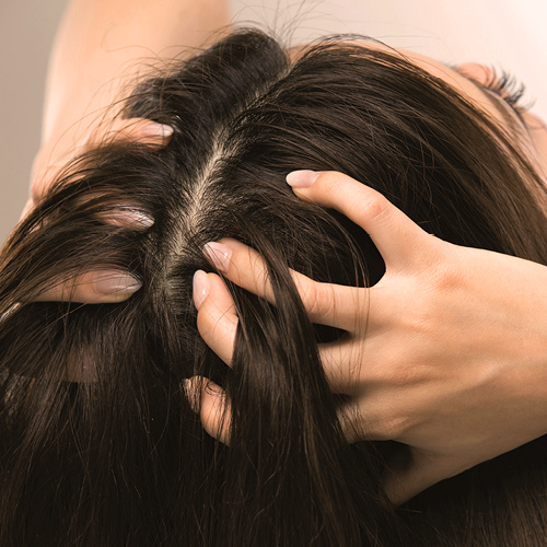 Ragazza che si mette le mani dei capelli che apparentemente sembrano sporchi